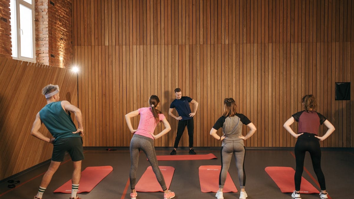 People stretching on yoga mats during a fitness class indoors.